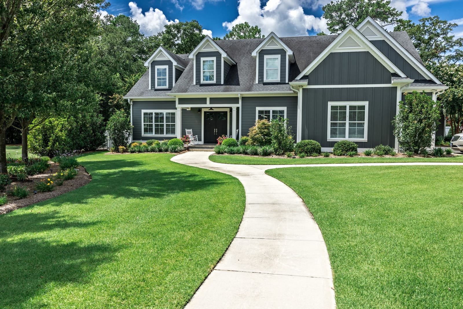 Craftsman home with a curved walkway and manicured landscaping