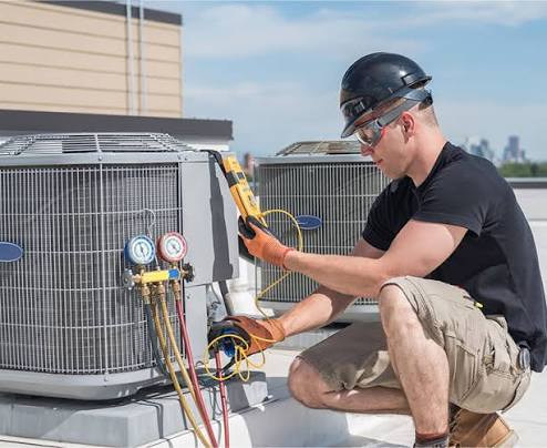 All American Discount Air technician checking refrigerant gauges on a rooftop AC unit