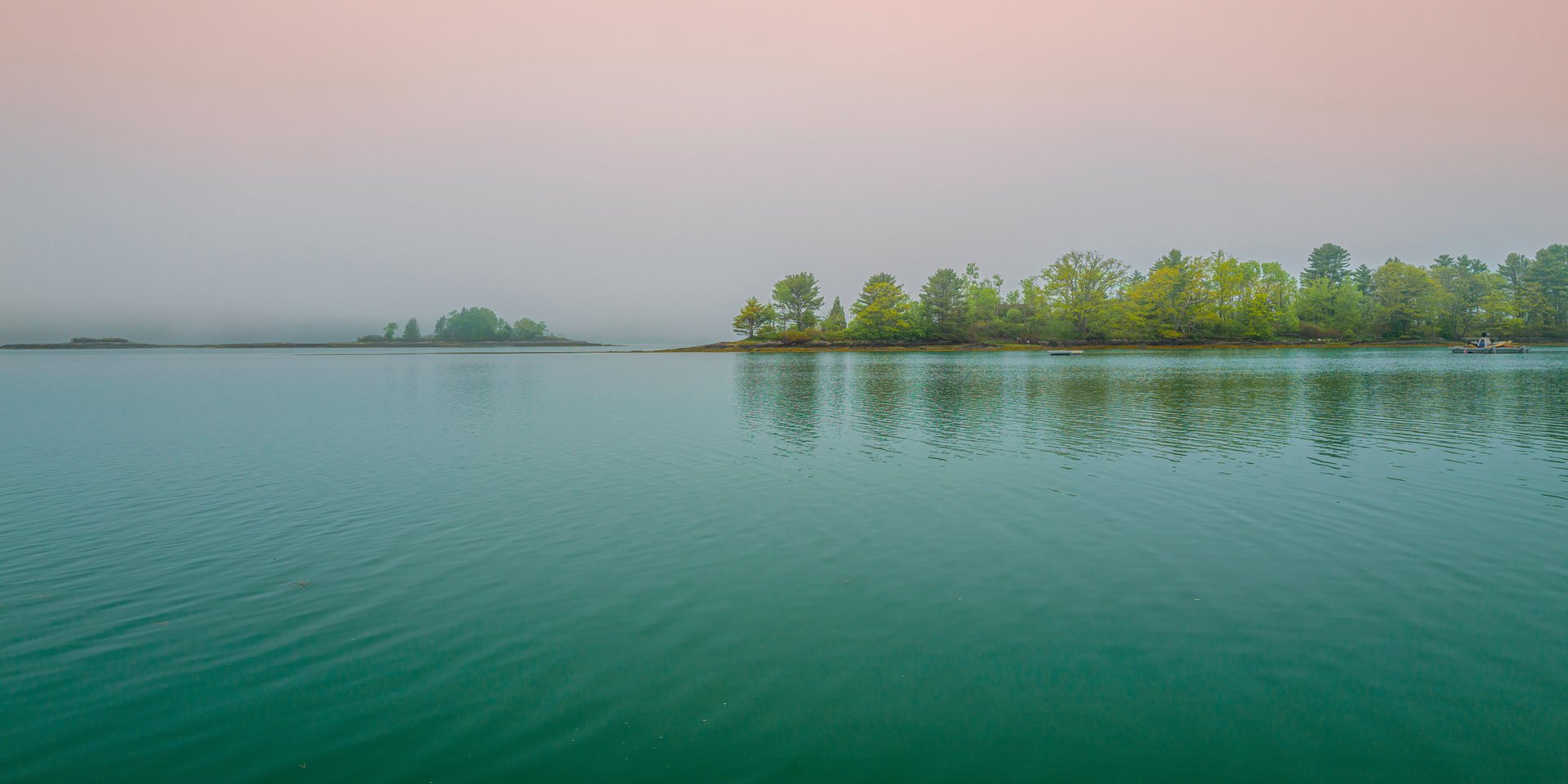 First light over calm coastal water beside a waterfront campsite