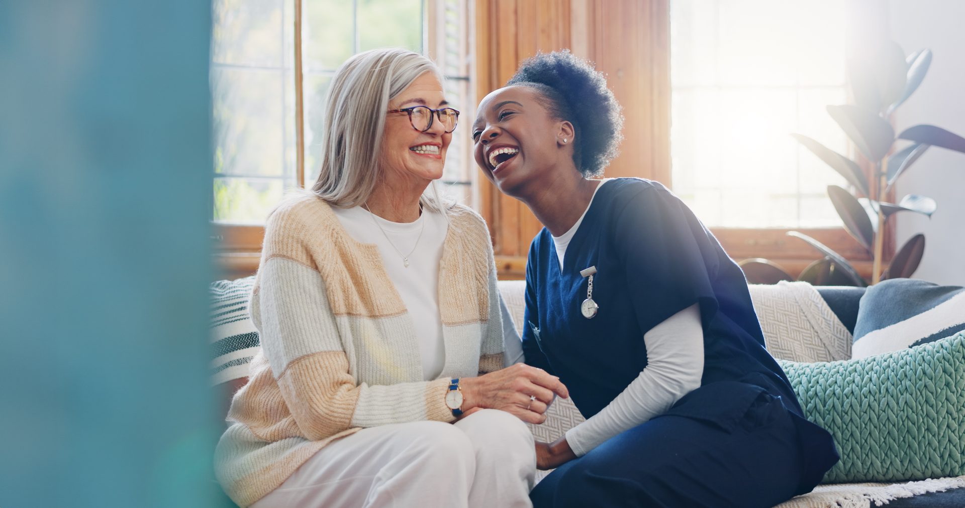 Caregiver and client laughing together on the sofa during a home visit